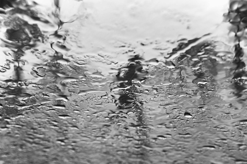 A monochrome shot of the rain droplets on a window