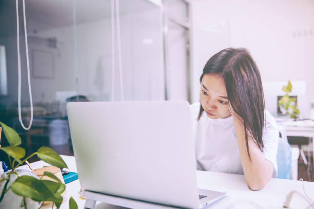 istock Tired staff with head in hand sitting at computer desk in office 1170439493