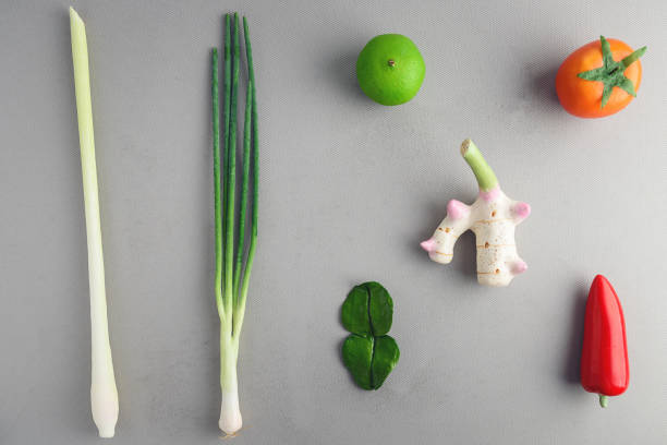 Lime, tomato, galangal, kaffir lime leaves, lemongrass, red chilli prepared to make Tom Yum soup on gray cloth.