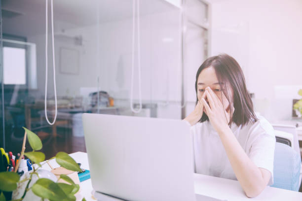 istock Tired staff with head in hand sitting at computer desk in office 1170446214