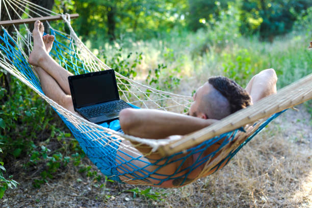 istock Freelancer working on a laptop lying in a hammock. 1170446896