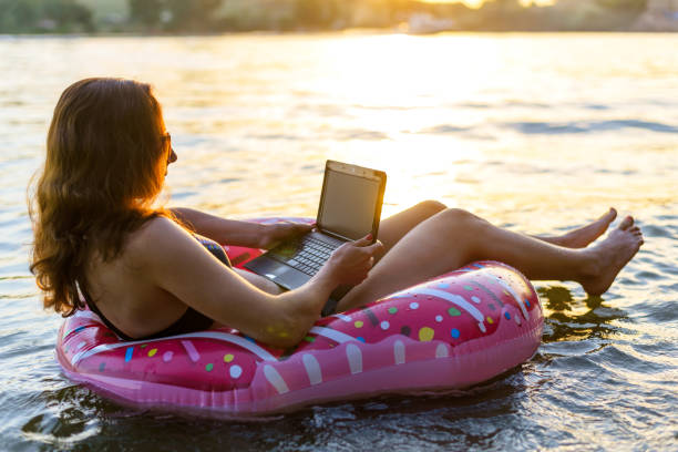 istock Business woman freelancer working on a laptop while sitting on a rubber inflatable donut, on a sunset background. 1170448401