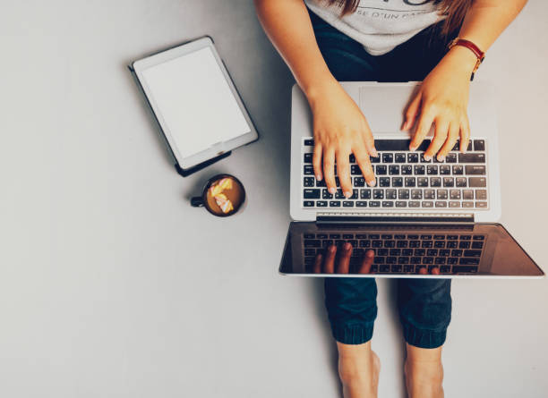 istock Young woman working on laptop computer while sitting on the floor and holding hot coffee, vintage tone. 1170449142