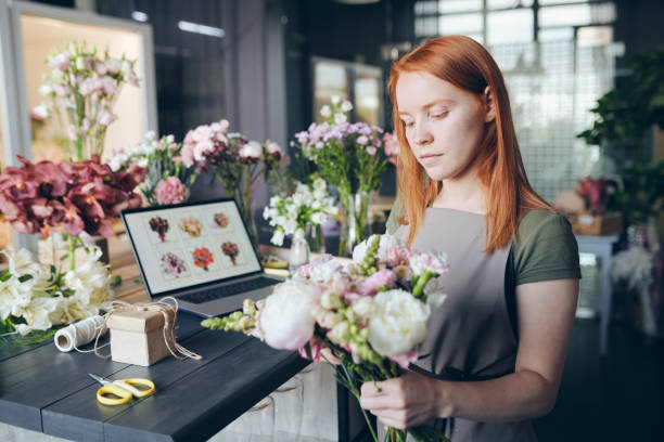 mischen von blumen in bouquet - women customer service representative service standing stock-fotos und bilder