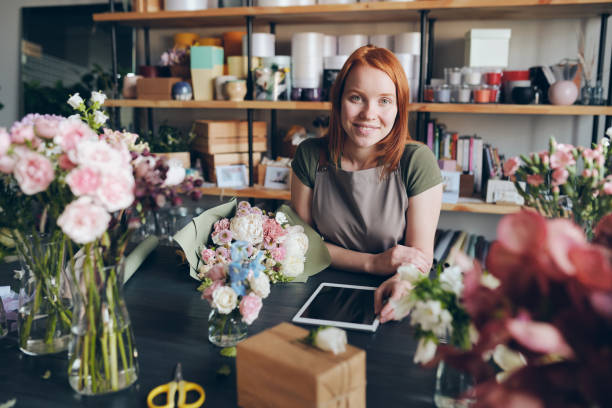 working in cozy flower shop - flower computer young women selling imagens e fotografias de stock