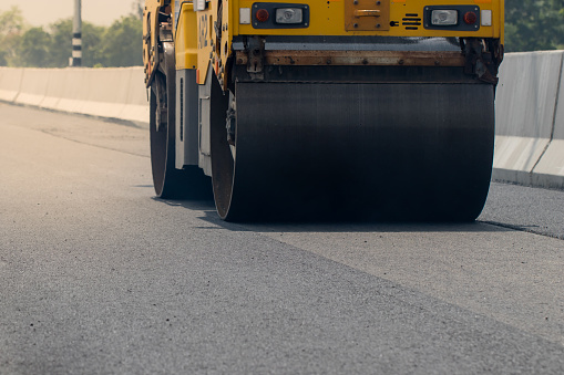 Asphalt road surface is smoothed with steel wheels, road construction machinery, asphalt paver