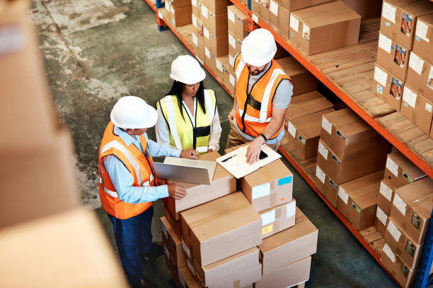 Planning out logistical processes High angle shot of a group of factory workers having a discussion in a warehouse logistical stock pictures, royalty-free photos & images