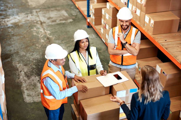 Leave it to the logistical specialists High angle shot of a group of factory workers having a discussion in a warehouse logistical stock pictures, royalty-free photos & images