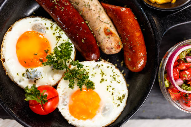 istock Fried eggs sunny side up served with sausage in a cooking pan 1170460781