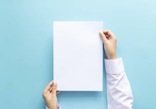 close up hands holding  empty white blank letter paper size A4 for flyer or invitation mock up isolated on a blue background.