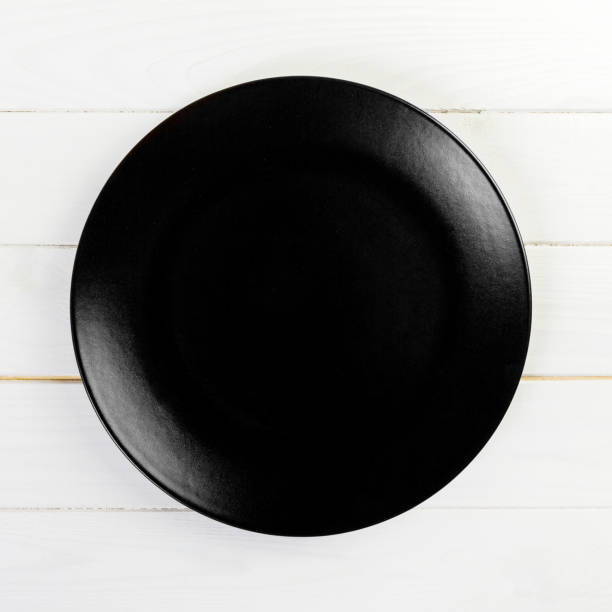 istock Black round plate on wooden background, top view, copy space 1170463223