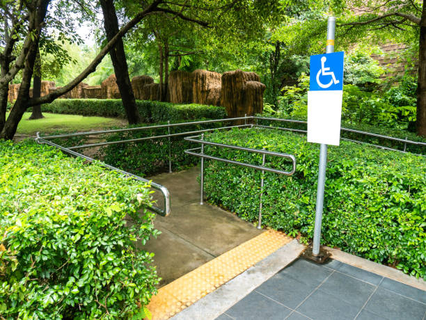 maneira concreta da rampa com corrimão do aço inoxidável e sinal deficiente para a cadeira de rodas da sustentação pessoas deficientes no parque. - disablement - fotografias e filmes do acervo