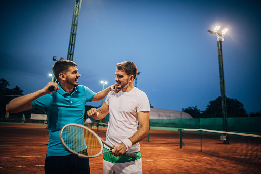 Two men, tennis players fair play after a match on tennis court.