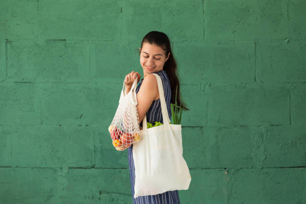 婦女購買水果和蔬菜與可重複使用的棉花生態產品袋。零浪費生活方式理念 - 環保袋 個照片及圖片檔