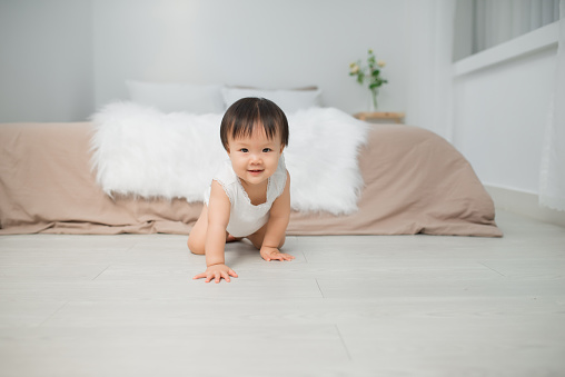 Little baby girl or girl crawling on floor in bed room