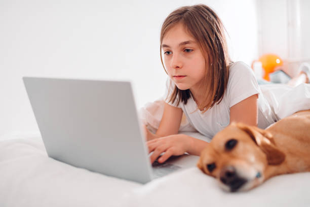 istock Girl lying on the bed with dog and using laptop 1170469234