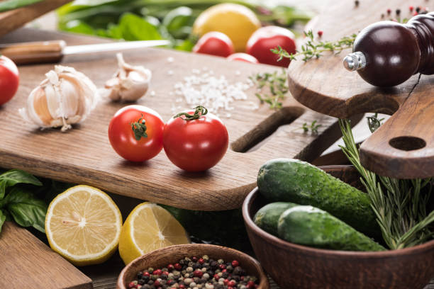 istock selective focus of cutting boards, cherry tomatoes, salt, garlics, cucumbers, pepper mill, greenery, lemons and spices 1170472964