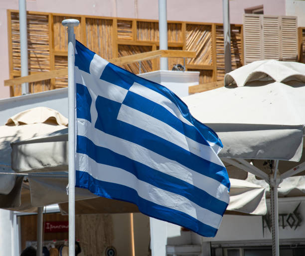 grecka flaga faluje przed parasolami przed kawiarnią fira na agiou ioannou - fire log zdjęcia i obrazy z banku zdjęć