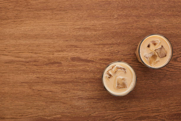 木製のテーブルの上のメガネでおいしいアイスコーヒーのトップビュー - カフェラテ　アイス ストックフォトと画像