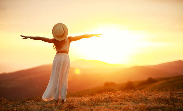istock Happy woman standing with her back on sunset in nature iwith open hands 1170478549