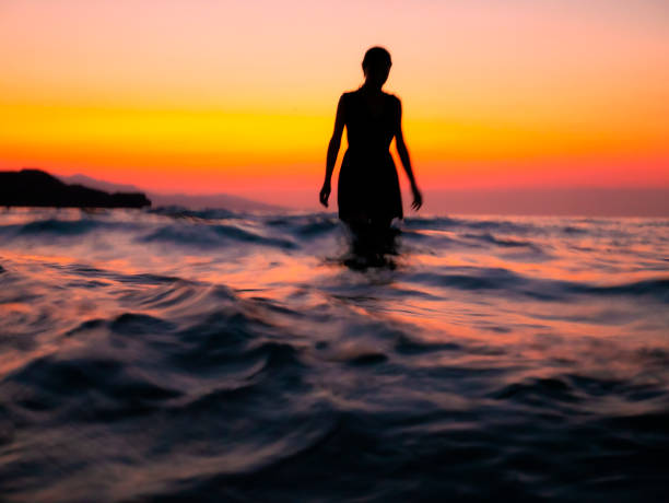 mädchen im meer bei sonnenuntergang - wading stock-fotos und bilder