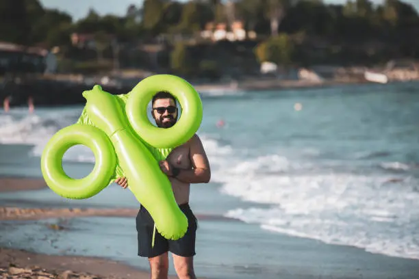 Mixed race man with beard holding green inflatable toy