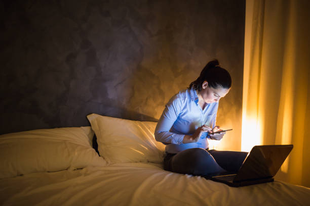 jeune femme d'affaires travaillant tard dans une chambre d'hôtel - hotel wireless technology bedroom hotel room photos et images de collection