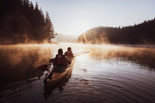 Kayaking on mountain lake. Couple rowing with kayak in lake at beautiful sunrise light. canoeing stock pictures, royalty-free photos & images