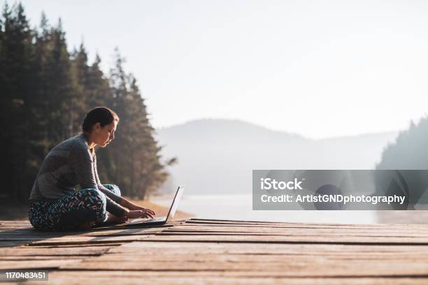 Woman Using Laptop Outdoor At Wooden Pier Stock Photo - Download Image Now - Remote Location, Working, Laptop