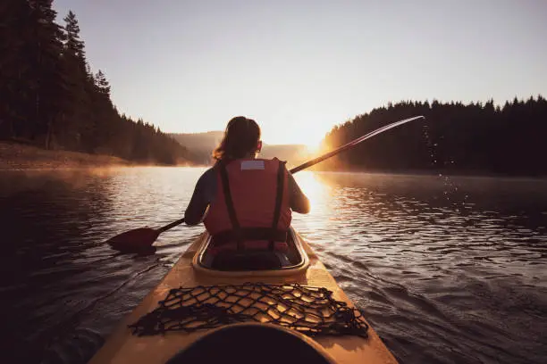 Photo of A woman with a kayak at the sunrise.