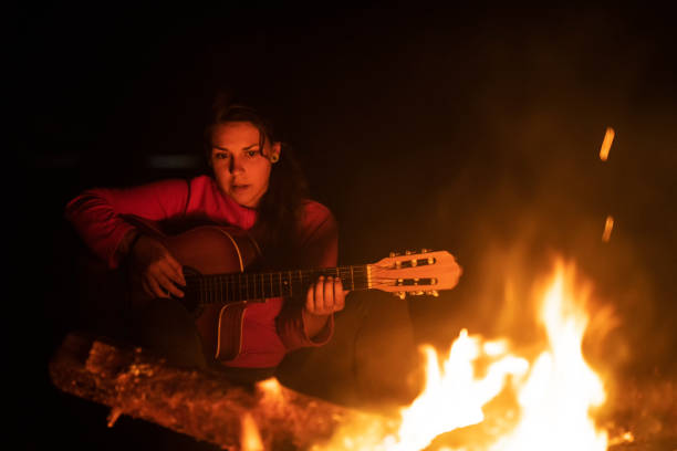 istock Latino woman play on guitar around the fire. 1170483576