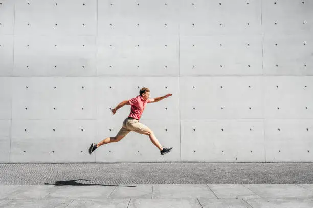 Young male tourist jumping by gray wall at Paul-Loebe-Haus