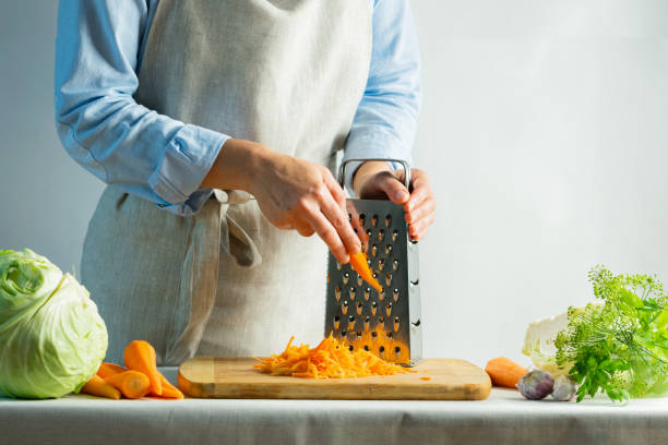 la femme râpe les carottes fraîches pour la salade de cuisson ou pour le fond naturel de chou de salage. concept de nourriture végétarienne. - grater photos et images de collection