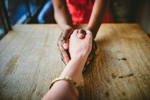 Shot of two unrecognizable women holding hands together on a table