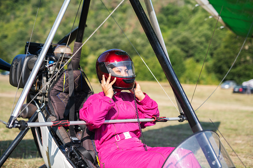 Pilot woman preparing protective helmet before flying with hang glider.