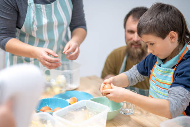 istock Boy breaking egg for cookies in cooking class 1170492391