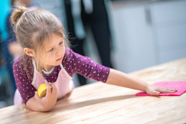 Girl cleaning table with a sponge in cooking class.
