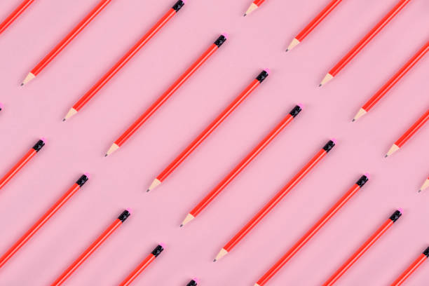 Erasable red colored pencils diagonal flat lay on pink background