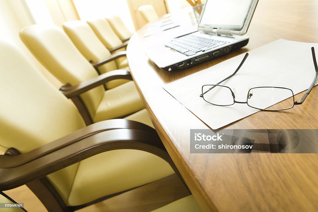 Boardroom Image of table with laptop, papers, glasses on it with chairs near by in row Armchair Stock Photo