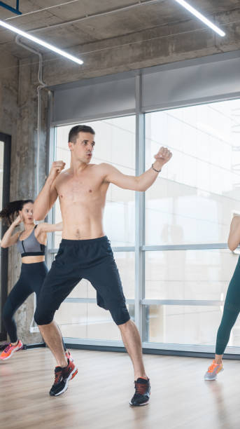 istock Fitness training in the bright studio - two young women training with their coach 1170499221