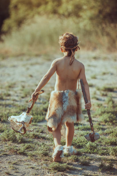 istock Caveman, manly boy with primitive weapon outdoors. Ancient prehistoric warrior 1170499401