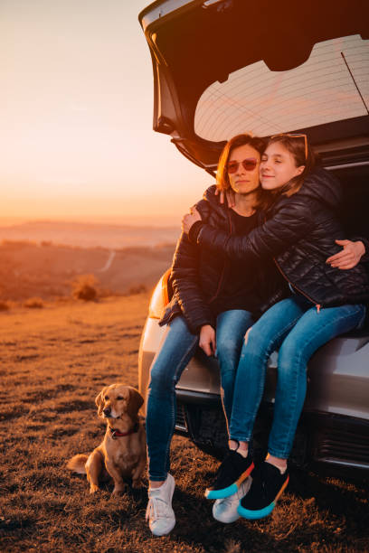 istock Daughter embracing mother while sitting in car trunk 1170503586