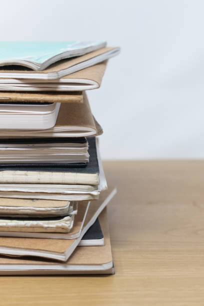 istock Stack of worn used notebooks on a wooden table top 1170505214
