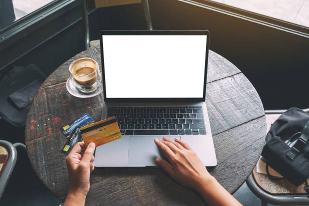 istock a hand holding credit card while using and typing on laptop with blank white screen and coffee cup on wooden table 1170505999
