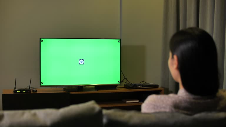 Woman Looking at TV with Green screen at Night