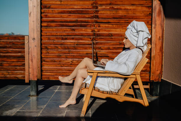 istock Woman in bathrobe sitting at the balcony and using laptop 1170509140