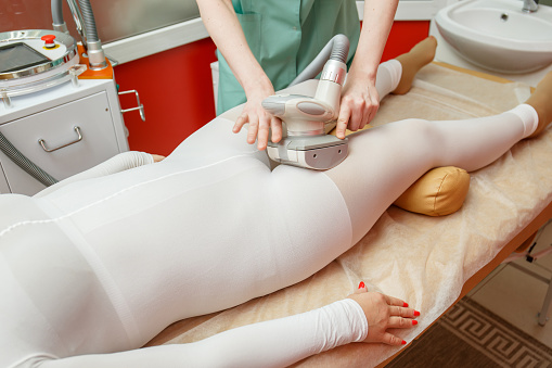 Woman having anti-cellulite lpg massage treatment with apparatus in beauty salon