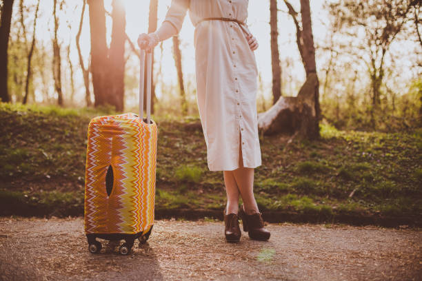 istock Young woman pulling a suitcase in the park on a sunny day 1170510712