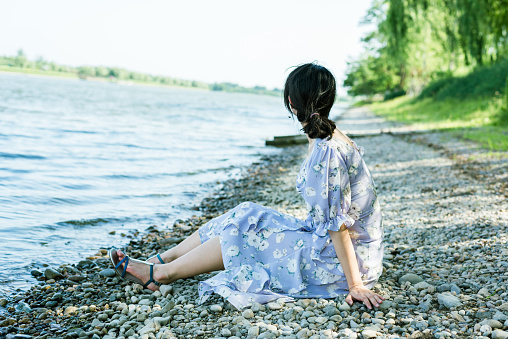 Summer time, young woman on river bank