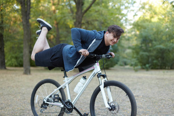 istock Young handsome caucasian man smiling performs stunt legs up on the bicycle at green park. Risky trick. 1170512921